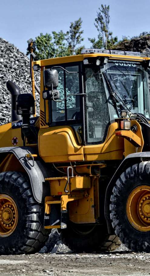 Un engin de chantier Volvo jaune avec un pare-brise cassé.