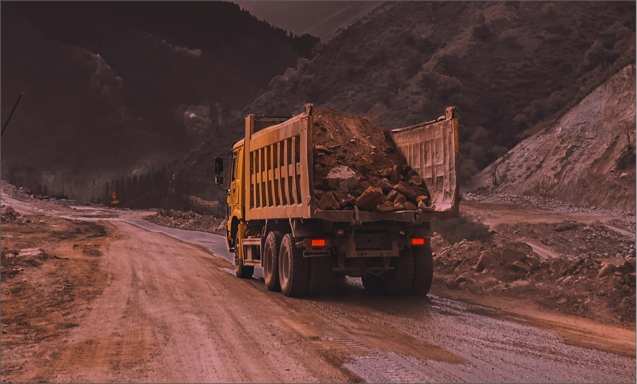 photo de camion jaune dans une carrière vue arrière transportant des cailloux dans sa benne